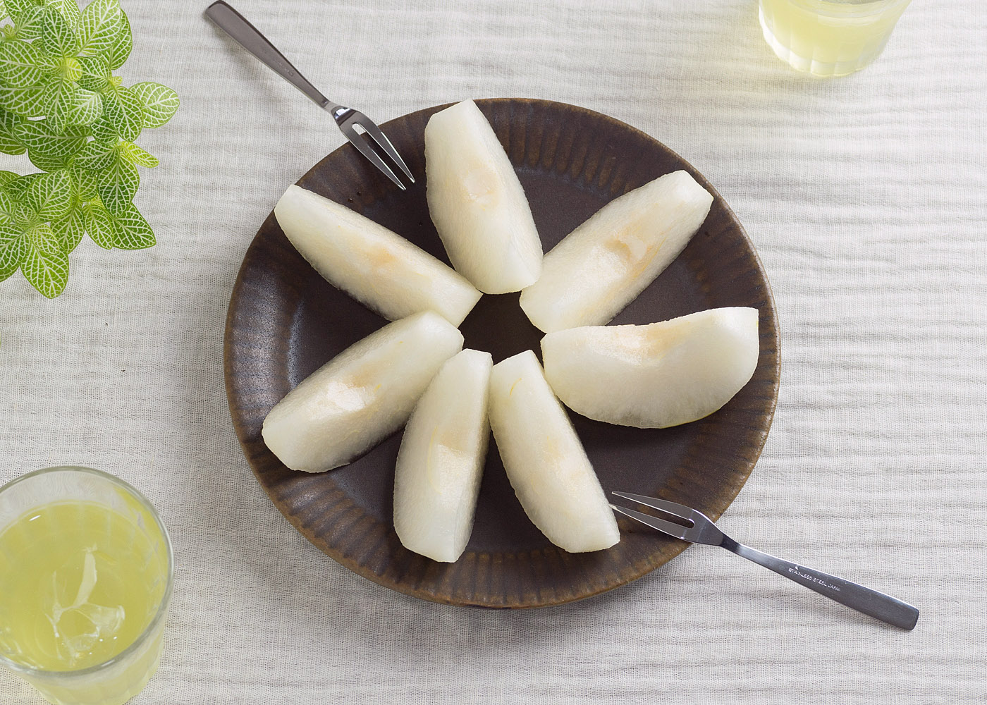 真っ白な梨と焦げ茶色のラッフルプレートのコントラスト